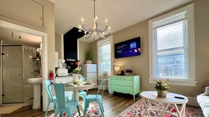 Una cocina moderna con zona de comedor, un televisor montado en la pared y un tapete floral.