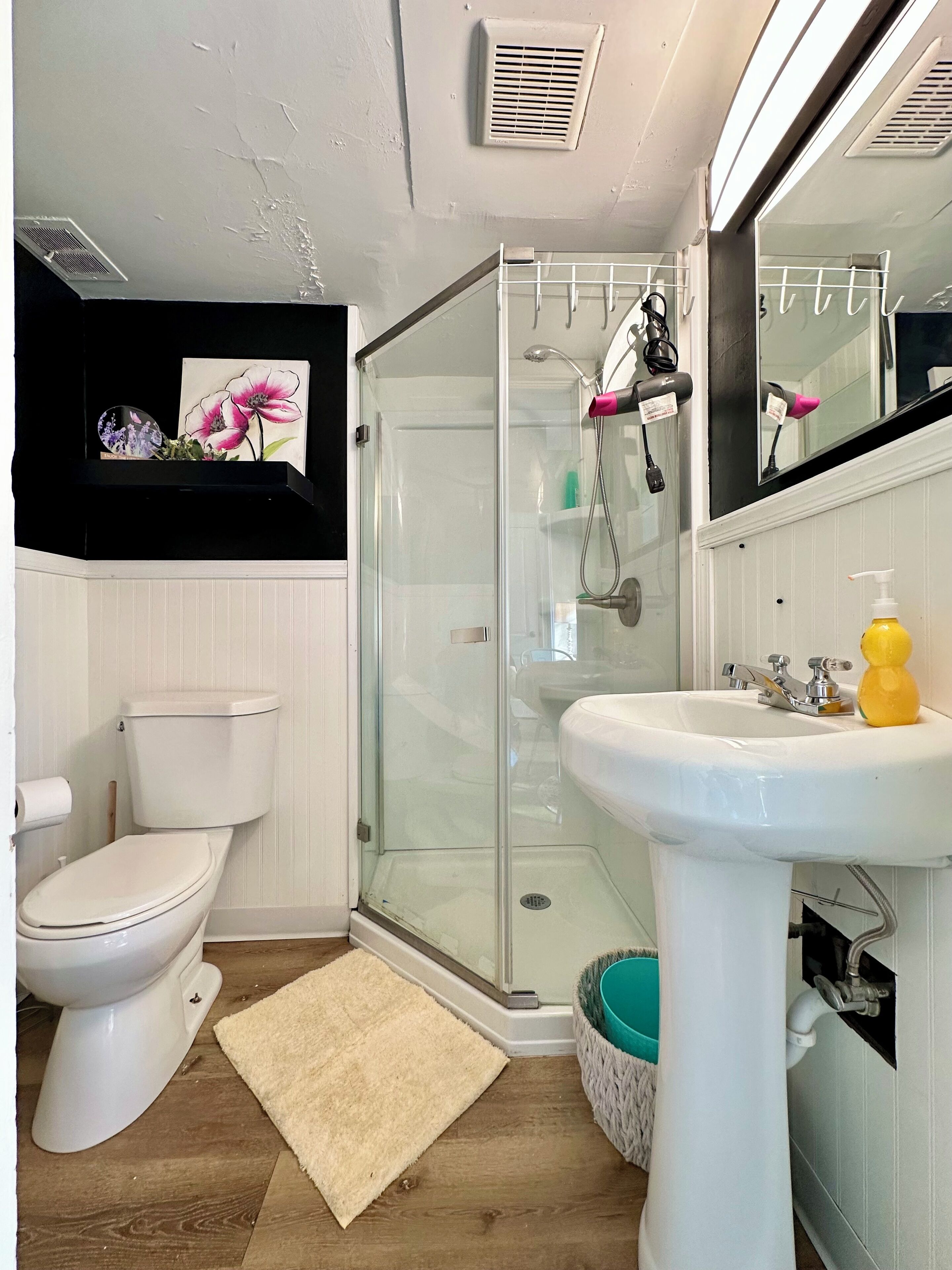 A bathroom with a toilet, glass shower enclosure, sink, and a mirror.