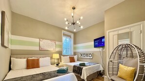 Habitación de hotel con dos camas, una silla colgante, un televisor y un cartel que dice "XOXO".