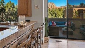 Una cocina con barra, un cactus y vistas a un paisaje montañoso a través de grandes puertas correderas de vidrio.