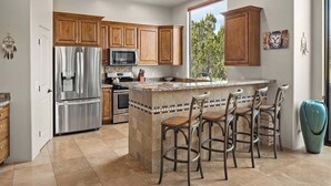 Una cocina moderna con armarios de madera, electrodomésticos de acero inoxidable y una isla central con taburetes de bar.