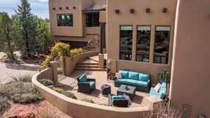 Una casa moderna con un patio curvo, mobiliario exterior y una planta de cactus.