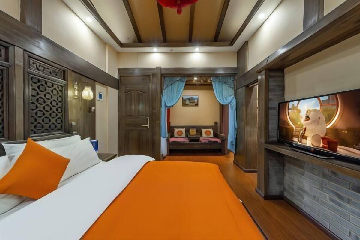 A hotel room with a bed, a television, a seating area, and a fireplace.