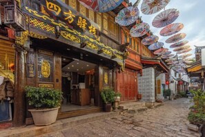 A traditional building with a wooden facade, large potted plants, and a sign with Chinese characters. - Lijiang Sifang Inn (Lijiang)