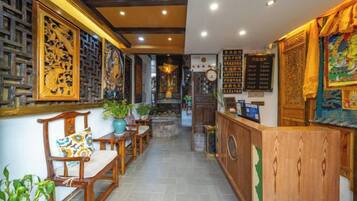 Decoração tradicional com móveis de madeira, balcão de recepção e obras de arte nas paredes.