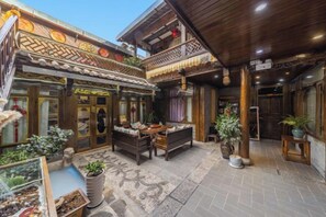 A traditional courtyard with a wooden bench, potted plants, and a glass display case.