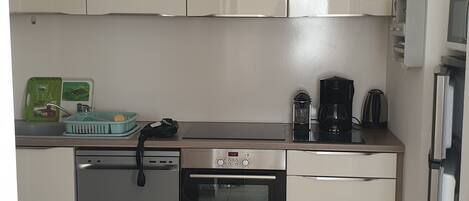 A compact kitchen with a dishwasher, oven, and a coffee maker.