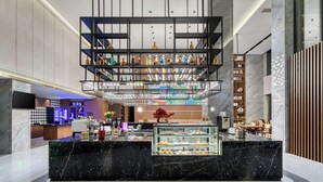En modern hotellobby med en receptionsdisk i marmor, en flervåningshylla med flaskor och en sittgrupp avskild med en trävägg.