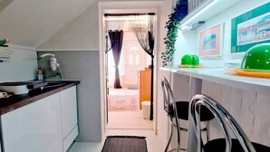 Een smalle keuken met een eethoek, een spoelbak en een kleine koelkast.