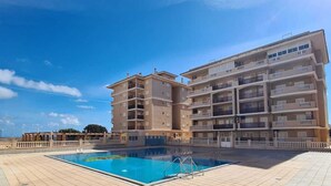 A multi-story building with a swimming pool in the foreground. - Spacious, family-friendly apartment, 5 min from La Mata Beach (La Mata)