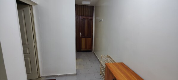 En smal hall med en trädörr längst in, en träbänk och ett klinkergolv.