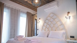 A neatly made bed with folded towels, a wooden ceiling, and a white wall with a decorative light fixture. -  La Rubina Alacati-Adults Only (Cesme)