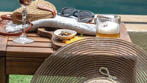 A table with a glass of beer, a woven bag, a pair of sunglasses, and a bowl of nuts by a poolside. -  La Rubina Alacati-Adults Only (Cesme)