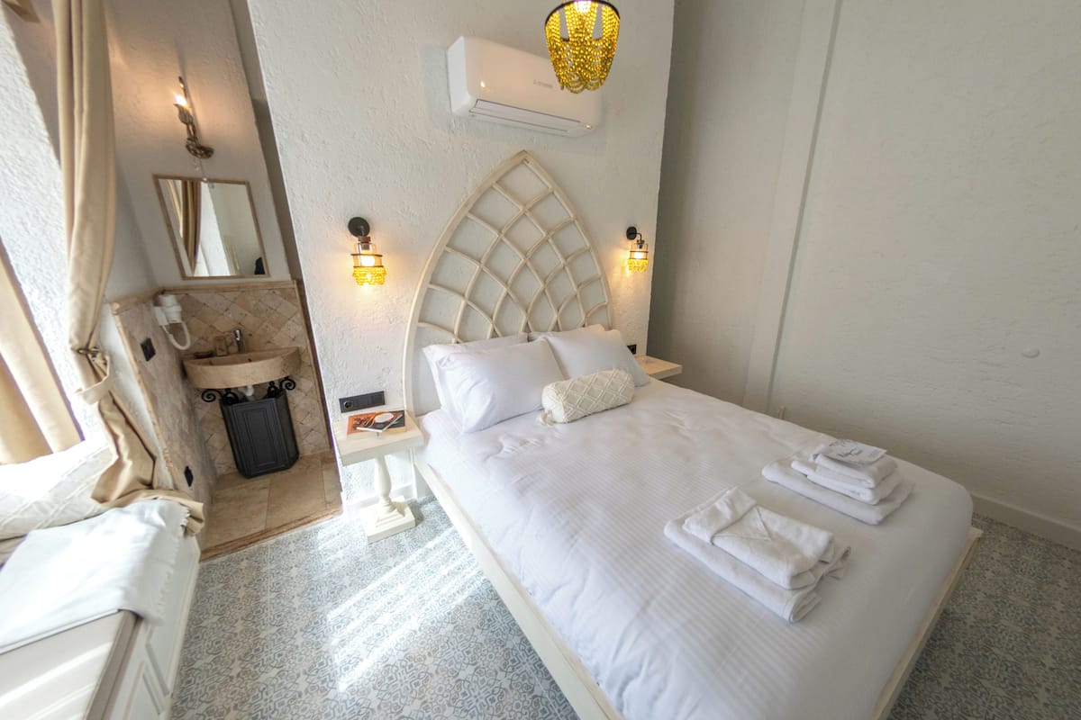 Une chambre d’hôtel avec un lit, une table de chevet et une coiffeuse avec un miroir.