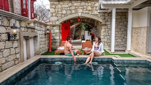Un bâtiment en pierre doté d’une piscine, d’un espace extérieur aménagé et d’une porte rouge.