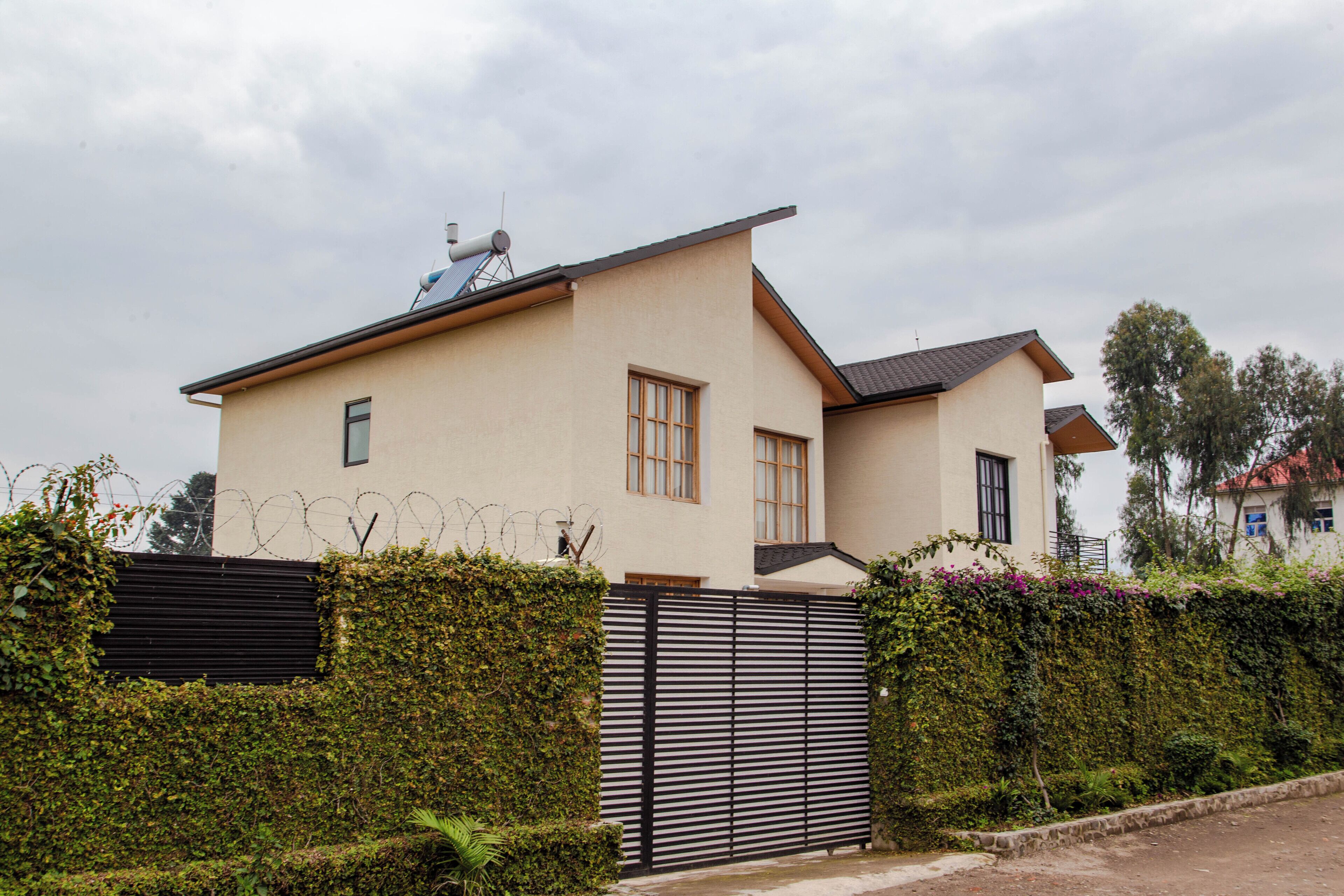 Een modern herenhuis met twee verdiepingen, een plat dak, een schotelantenne en een hekpoort.