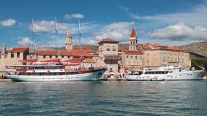 Un port où sont amarrés des bateaux, un bâtiment historique avec un toit rouge et une tour avec une horloge.