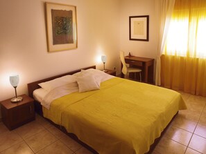 Une chambre d’hôtel comprenant un lit, un bureau, une chaise et deux lampes de chevet.