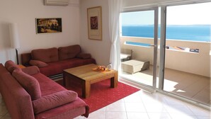 Un salon avec un canapé, une table basse et un balcon offrant une vue sur la mer.
