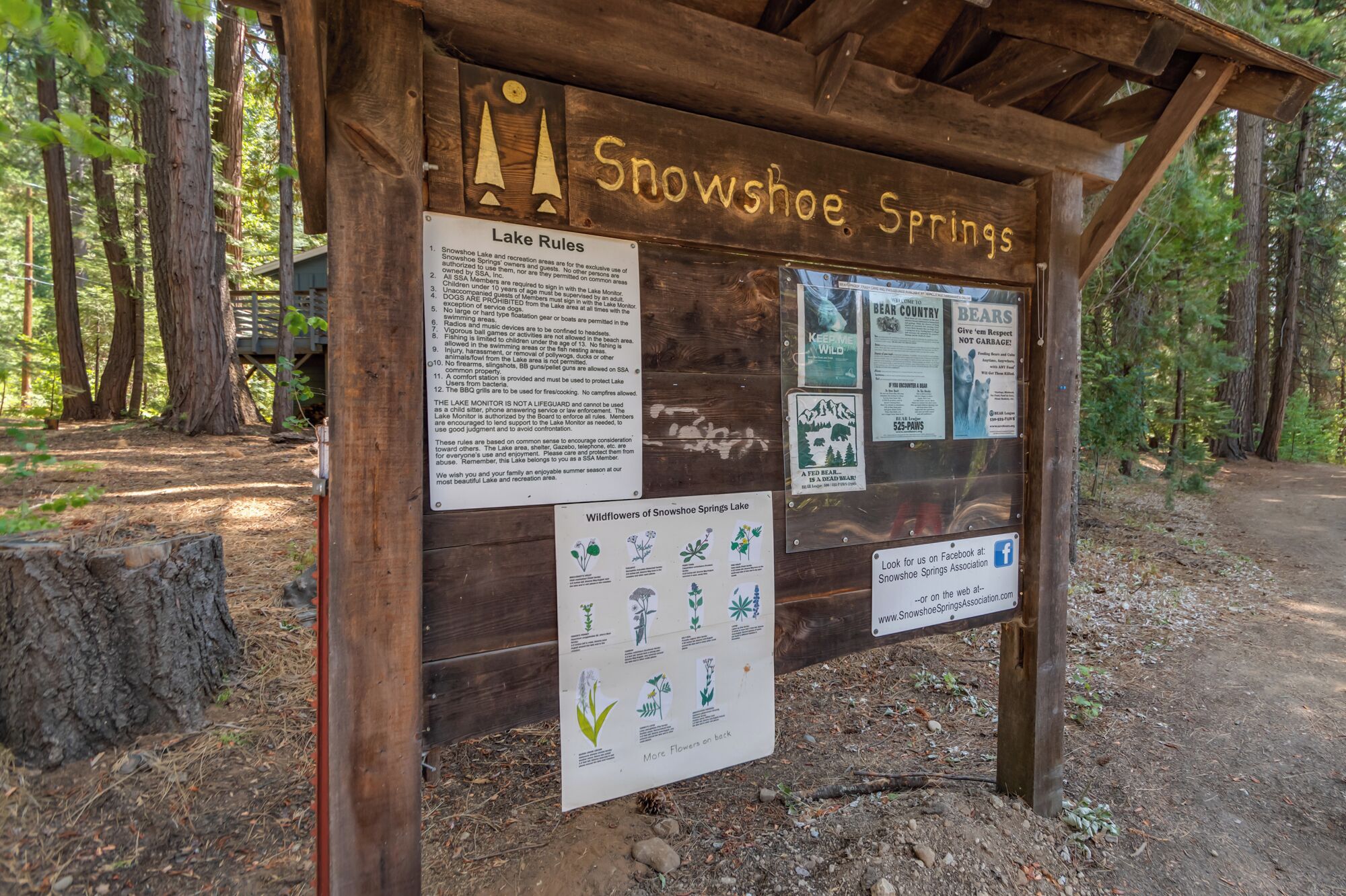 Ein hölzernes Schild am Snowshoe Springs mit verschiedenen Informationsplakaten und einem Facebook-Link.
