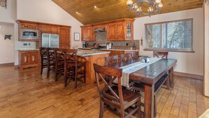A spacious kitchen with wooden cabinets, a central island, and a dining area with a large table and chairs.
