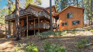 A wooden cabin with a balcony and a separate building, surrounded by trees.