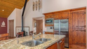 A kitchen with granite countertops, stainless steel appliances, wooden cabinets, and a black chimney.