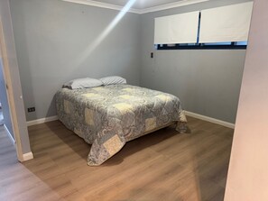 A bedroom with a bed, a window with blinds, and a wooden floor. - The Dreamy Retreat in Averley (Aveley)