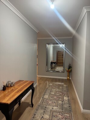 A hallway with a wooden bench, a patterned rug, a mirror, and a vase with flowers. - The Dreamy Retreat in Averley (Aveley)