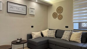 Una sala moderna con un sofá seccional gris, una pequeña mesa redonda y una cita motivacional enmarcada en la pared.
