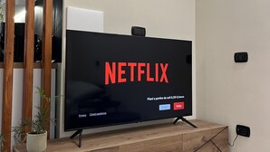Una sala de estar moderna con un televisor de pantalla plana montado en una consola de madera, un equipo de aire acondicionado arriba y un enchufe en la pared.