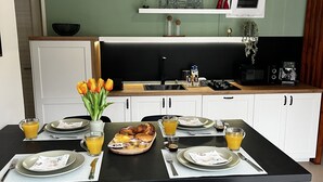 Una cocina moderna con una mesa para el desayuno, que incluye cruasanes, jugo y café.