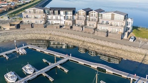 Une propriété située au bord de l’eau, dotée d’une marina, de bâtiments à plusieurs étages avec balcons, d’un quai et de bateaux.
