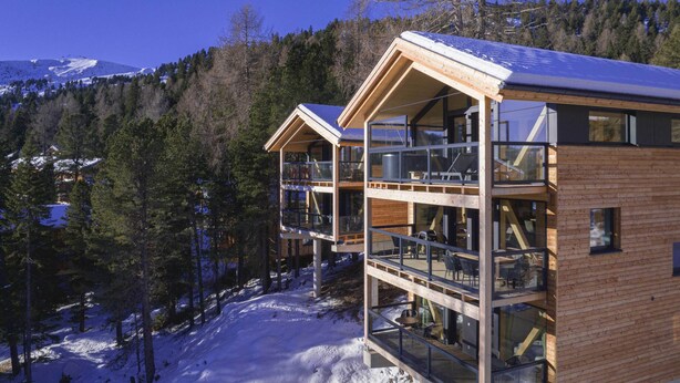 A modern wooden cabin with multiple balconies, surrounded by a snowy forest and mountains in the background. - Chalet in Turrach Near Ski Lift (Stadl-Predlitz)