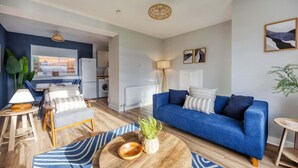 A modern living room with a blue sofa, wooden coffee table, and striped rug.