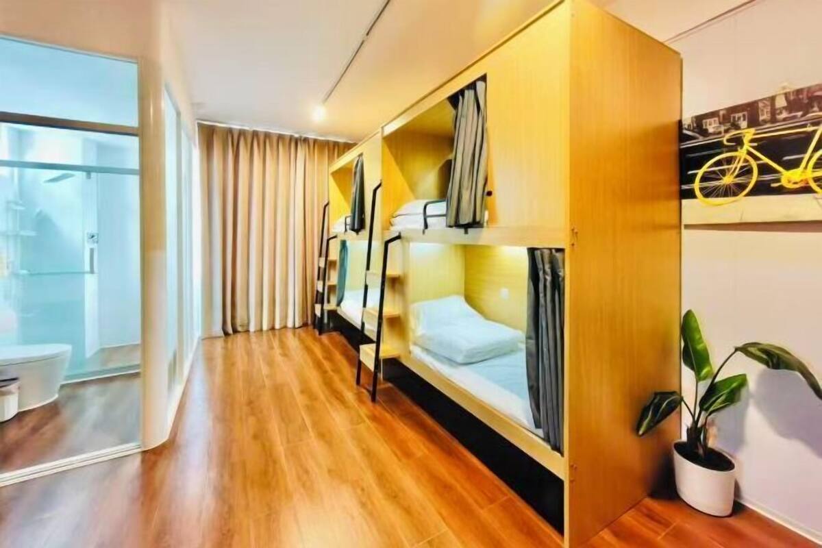 Ein Hotelzimmer mit einem Holzbett, einem Blumentopf, einem Fahrradbild an der Wand und einem großen Fenster.