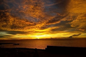 A sunset over a body of water with a distant shoreline.
