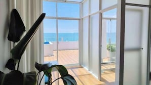 A room with a large window, a plant, and a door leading to an outdoor area.