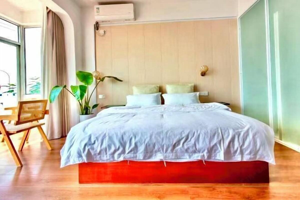 Ein Schlafzimmer mit Bett, Stuhl, Pflanze und Fenster.