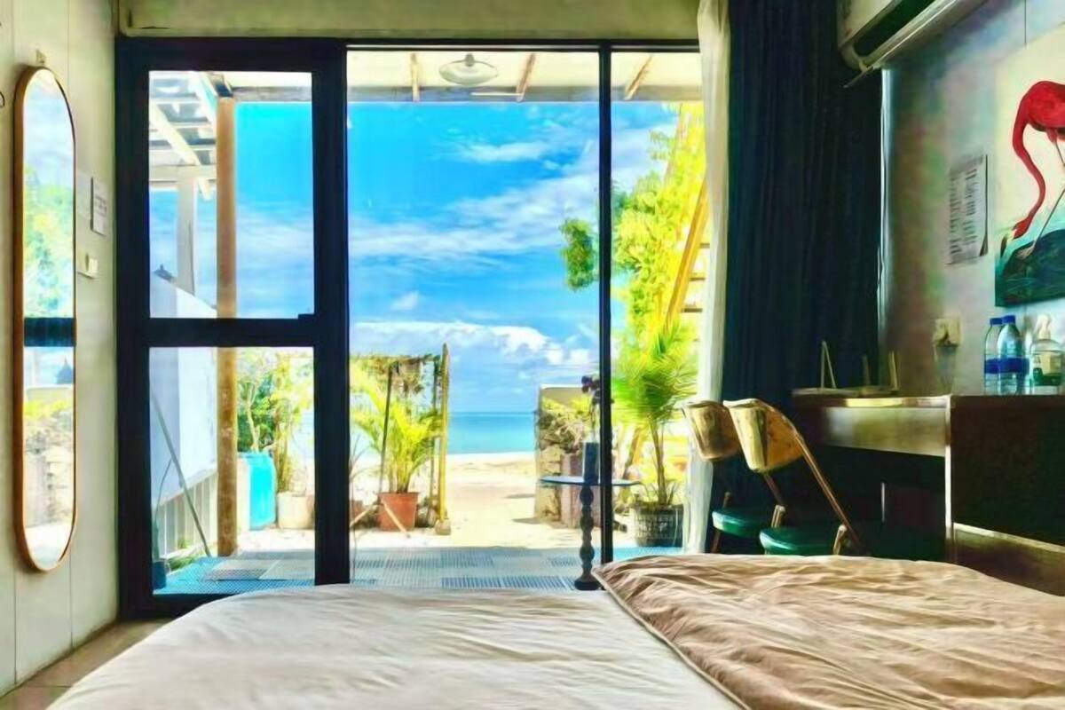 Ein Schlafzimmer mit einem Bett, einem Schreibtisch und Blick auf den Strand.