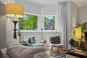Un salón acogedor con un sofá, una mesita, una lámpara y vistas a un balcón.