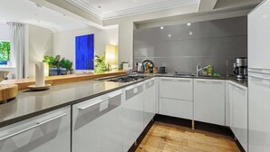 A modern kitchen with a central island, white cabinetry, and a large window with curtains.