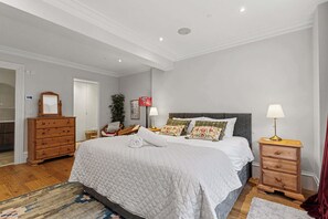 A bedroom with a large bed, a dresser, a nightstand, and a mirror. - Elegant West End Flat in Glasgow (Glasgow City)