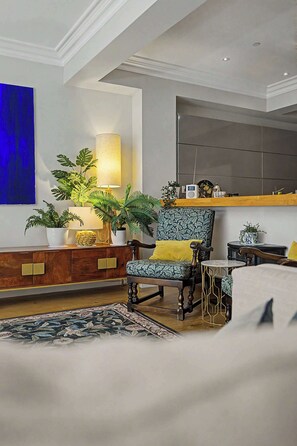 A living room with a sofa, a patterned armchair, a wooden cabinet, and a blue abstract painting on the wall. - Elegant West End Flat in Glasgow (Glasgow City)