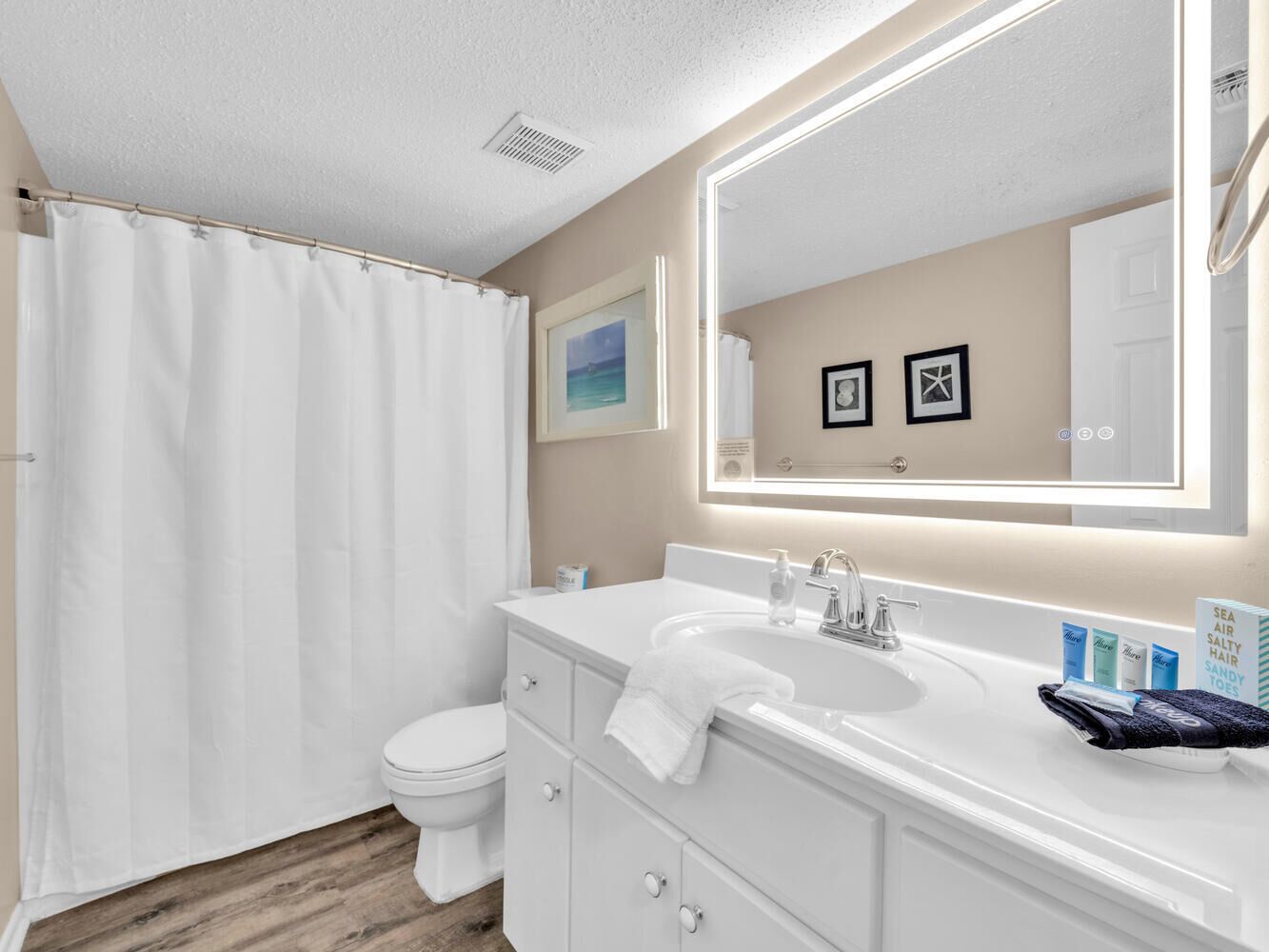 Een badkamer met een wit toilet, een wastafel met een spiegel erboven en een douchegordijn.