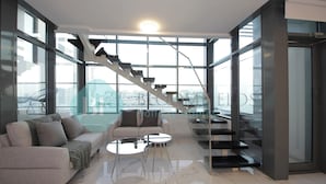 Ein modernes Wohnzimmer mit Sofa, Couchtisch und einer Treppe, die zu einer oberen Etage führt.