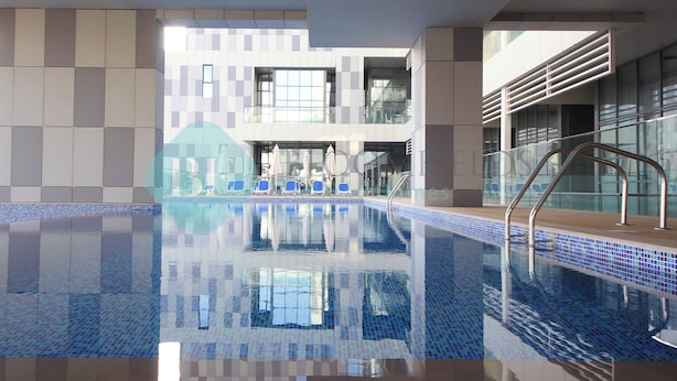 Ein Innenpool mit klarem, blauen Wasser, umgeben von modernen Fliesenwänden und einer Glasbrüstung.