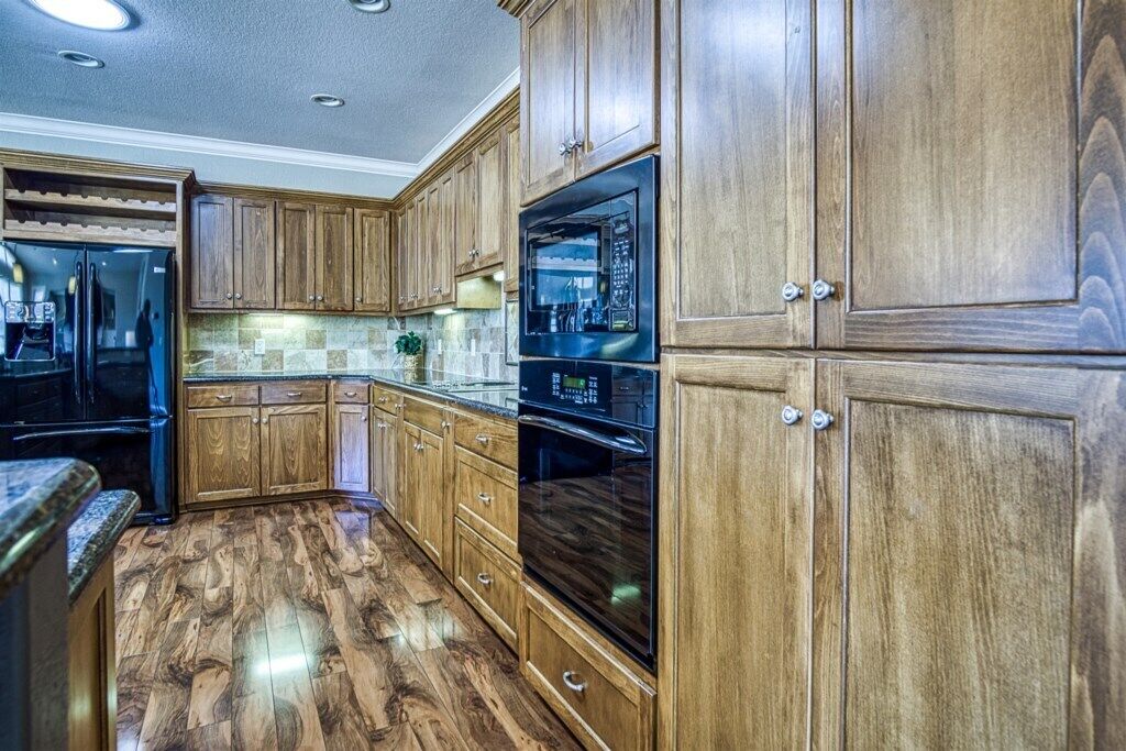 Eine Küche mit Holzschränken, einem schwarzen Kühlschrank und einem eingebauten Backofen.