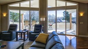 Amplia sala de estar con un sofá seccional grande, dos sillones y una mesa de centro. La habitación cuenta con grandes puertas corredizas de vidrio que dan a un patio exterior.