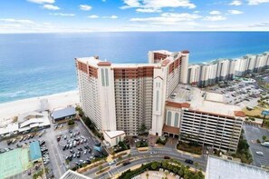 Un hôtel de grande hauteur, avec de nombreux étages, un parking et une vue sur la plage.